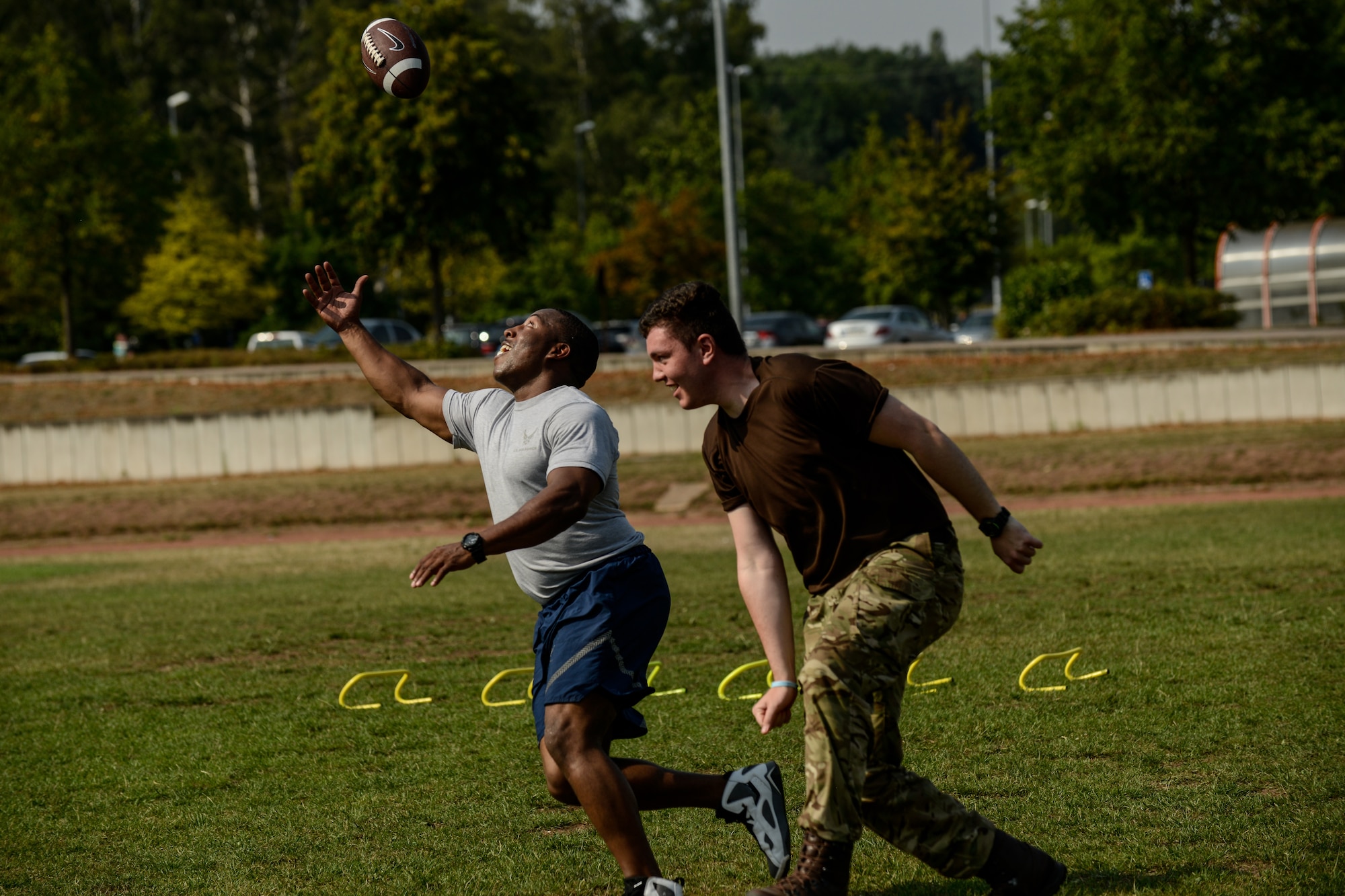 Staff Sgt. Darryl Brown, 786 Civil Engineer Squadron NCO in charge of vehicle control and a Royal Air Force Air Training Corps cadet, play football during an obstacle course Aug. 10, 2015, on Vogelweh, Germany.  The cadets completed four rounds of tire flips, football drills, speed work and sprints during the course hosted by the Kisling NCO Academy. (U.S. Air Force photo/Senior Airman Nicole Sikorski)