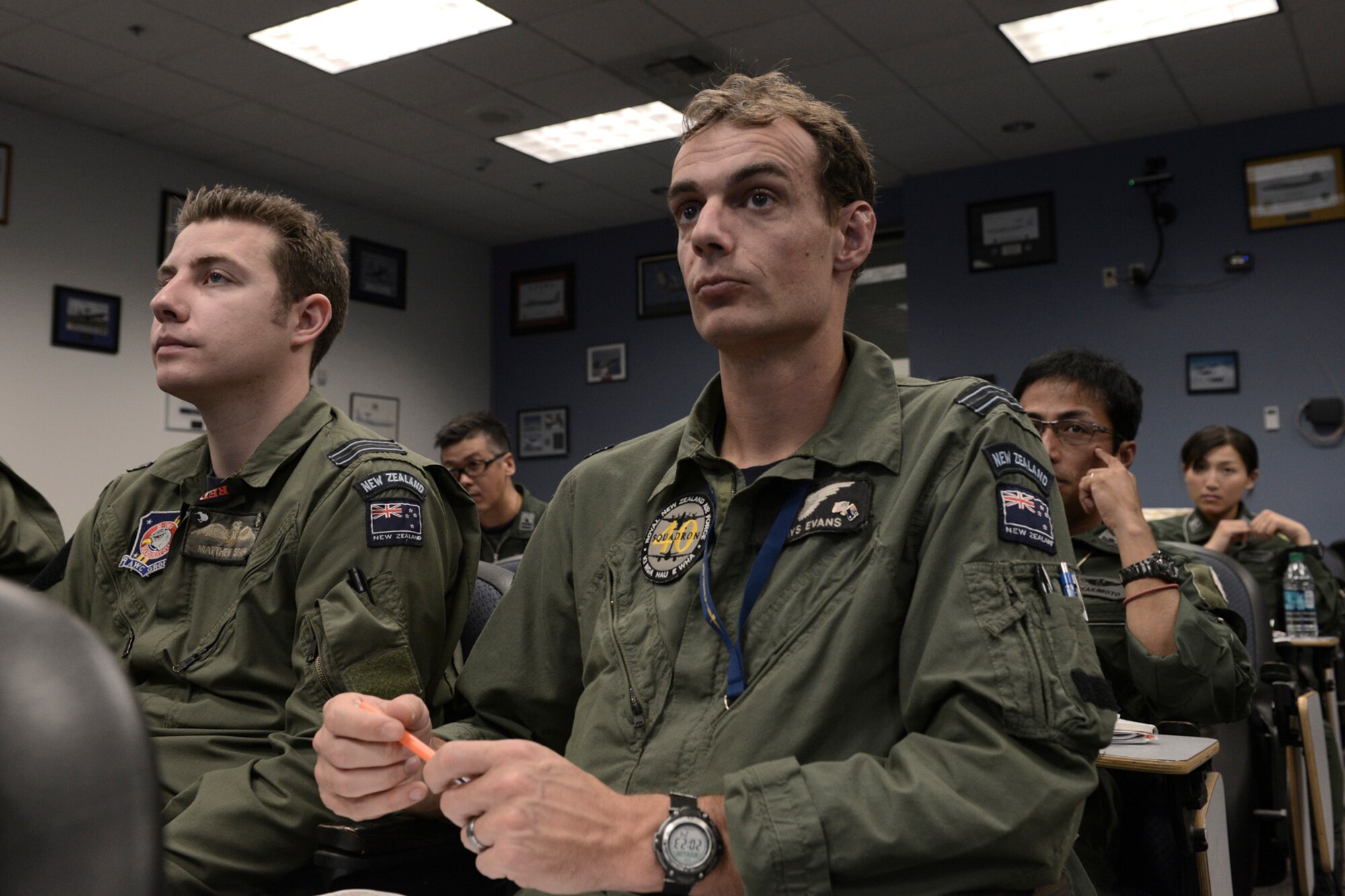 Aircrew with the Royal Australian Air Force, Royal New Zealand Air Force, and Japan Air Self-Defense Force, take notes for an upcoming flight during RED FLAG-Alaska at Joint Base Elmendorf-Richardson, Alaska. Mass briefings inform pilots of upcoming flight plans, weather and other information important to the safety and success for the upcoming mission. (U.S. Air Force photo by Staff Sgt. Cody H. Ramirez/Released)