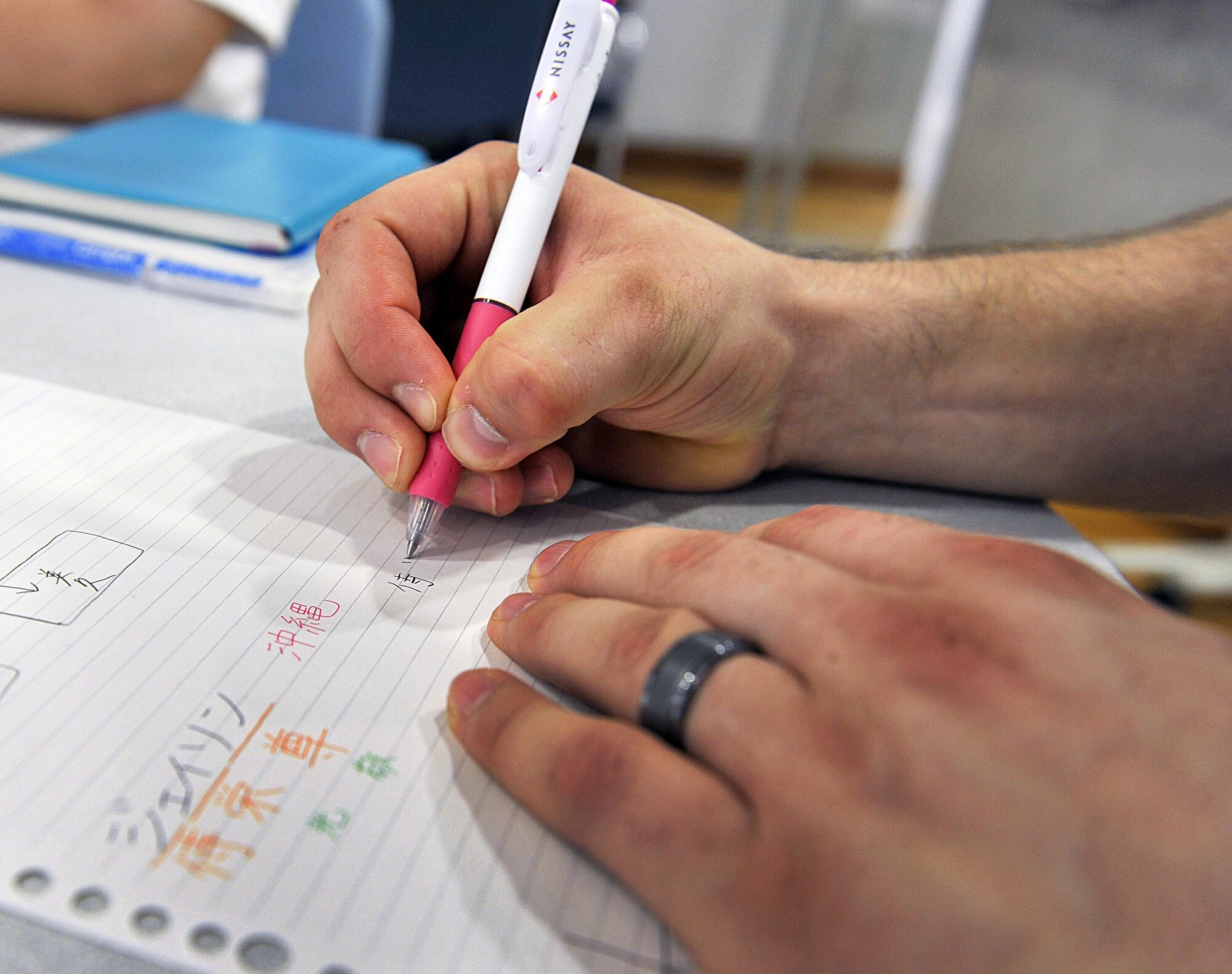 U.S. Air Force Senior Airman Jason Dwyer, 18th Communications Squadron cyber transport technician, writes his name in Kanji during a culture exchange at Kadena Rotary Plaza, Japan, Aug. 14, 2015. During the program, U.S. Air Force volunteers from the 18th Wing and KLI students increased friendship ties by exchanging their culture and language. (U.S. Air Force photo by Naoto Anazawa/Released)