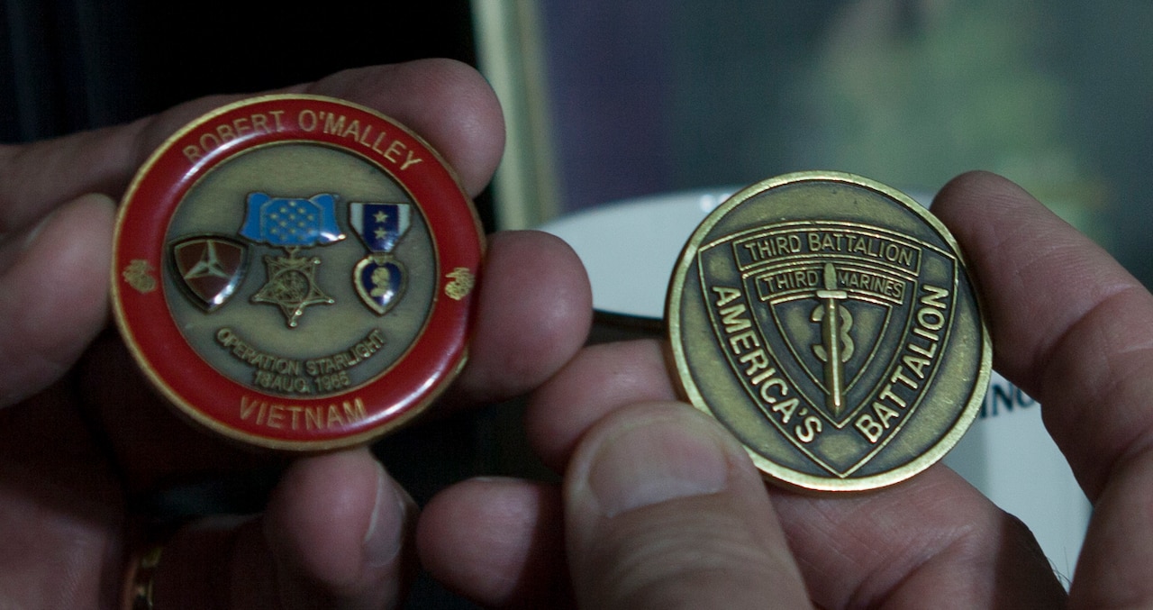 Charles "Charlie" Fink, Marine Vietnam veteran, holds specialty-made commemorative Marine Corps challenge coins June 2, 2015 at his home in Lake Butler. The coin on the left is for Marine veteran Sgt. Robert O’Malley, who was awarded the Medal of Honor for his actions during Operation Starlite.  