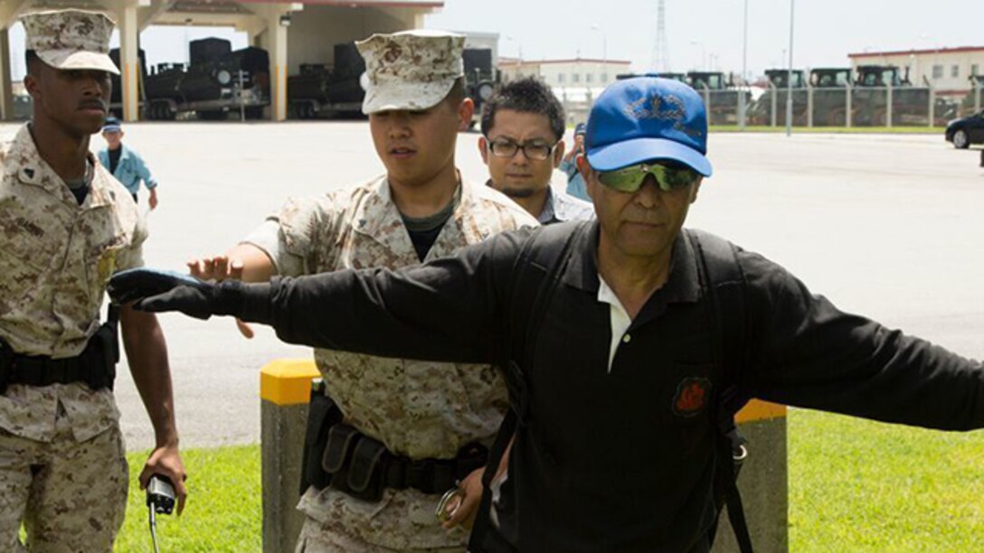 Lance Cpl. Kine Wang searches and detains a simulated suspect during bilateral, scenario-based training with the Ishikawa police on Camp Hansen, Okinawa, Japan, Aug. 5, 2015. The training increased teamwork between the local Japanese police and Marine personnel supporting the Provost Marshal's Office here. Wang, from Walls, Mississippi, is a security guard with 9th Engineer Support Battalion, 3rd Marine Logistics Group, III Marine Expeditionary Force. The U.S. Marine Corps Base Camp Smedley D. Butler's Provost Marshal's Office, Precinct North, Camp Hansen, was the lead Marine organization involved in the training.   