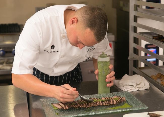 Staff Sergeant Hiram R. Carrion, an enlisted aide, prepares a food dish prior to an evening parade at Marine Barracks Washington, D.C., Aug. 14, 2015. The aides plan the menu for official events, shop for the menu items and prepare the dishes, all while documenting and accounting for every expenditure.(U.S. Marine Corps photo by Cpl. Christian Varney/Released)