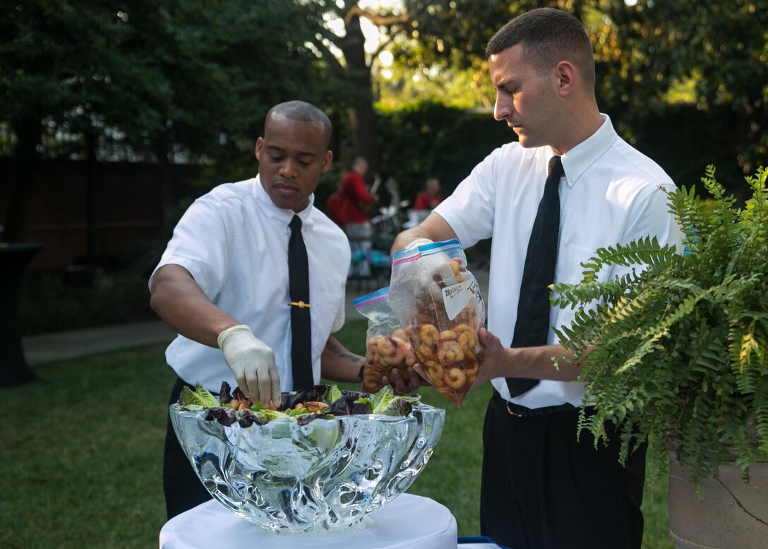 Two enlisted aides prepare a food dish prior to an evening parade at Marine Barracks Washington, D.C., Aug. 14, 2015. The aides plan the menu for official events, shop for the menu items and prepare the dishes, all while documenting and accounting for every expenditure.(U.S. Marine Corps photo by Cpl. Christian Varney/Released)