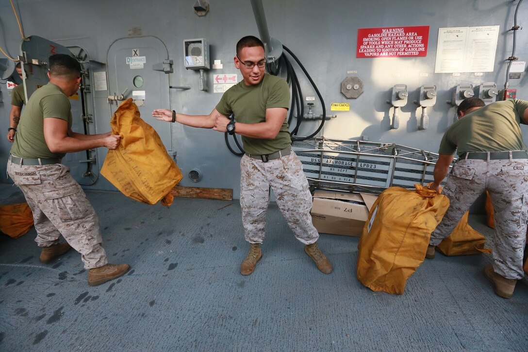 GULF OF ADEN (Aug. 15, 2015) U.S. Marine Cpl. Jose Martinez, middle, helps sort mail received from the USNS John Ericsson (T-AO 194) during a replenishment-at-sea. Martinez is an administrative clerk with Combat Logistics Battalion 15, 15th Marine Expeditionary Unit. The 15th Marine Expeditionary Unit is embarked aboard the amphibious transport dock ship USS Anchorage (LPD 23), part of the Essex Amphibious Ready Group, and is deployed in support of maritime security operations and theater security cooperation efforts in the U.S. 5th Fleet area of operations. (U.S. Marine Corps photo by Sgt. Steve H. Lopez/ Released)