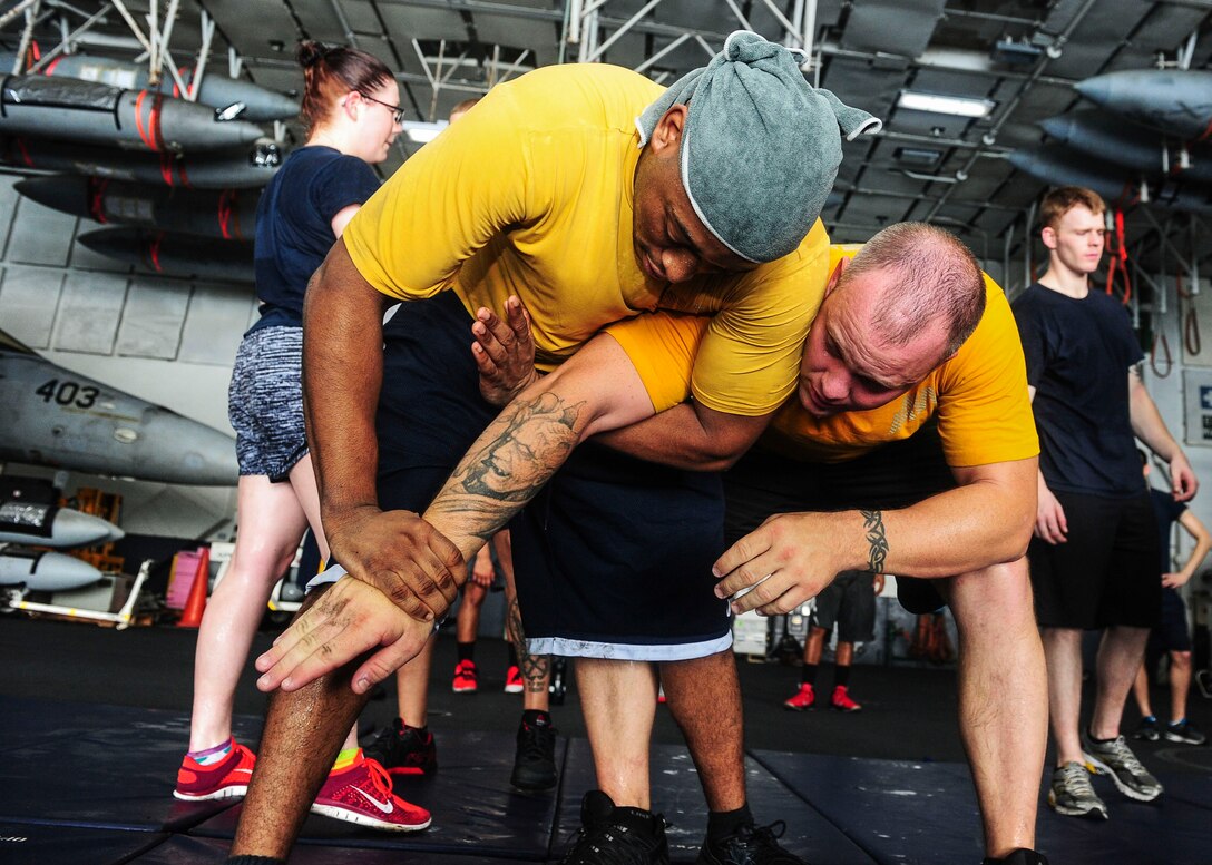 U.S. Navy Petty Officer 2nd Class Jamall Shuford performs a mechanical advantage control hold on Master-at-Arms 1st Class Joey Lawrence during a security forces training class in the hangar bay aboard the aircraft carrier USS Theodore Roosevelt in the Arabian Gulf, Aug. 20, 2015. The carrier is in the U.S. 5th Fleet area of operations supporting Operation Inherent Resolve, which include strike operations in Iraq and Syria as directed. U.S. Navy photo by Petty Officer 3rd Class Taylor L. Jackson