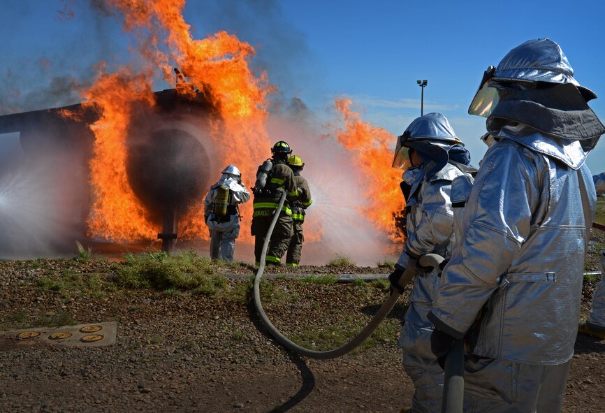 Air Commandos with the 27th Special Operations Civil Engineer Squadron provide extra hands while working with Clovis, N.M., firefighters to put out a simulated aircraft fire during an exercise Aug. 14, 2015 at Cannon Air Force Base, N.M. Air Commandos conducted joint fire training on base with a Clovis, N.M., fire department as part of a mutual aide agreement. (U.S. Air Force photo/Staff Sgt. Alexx Mercer)