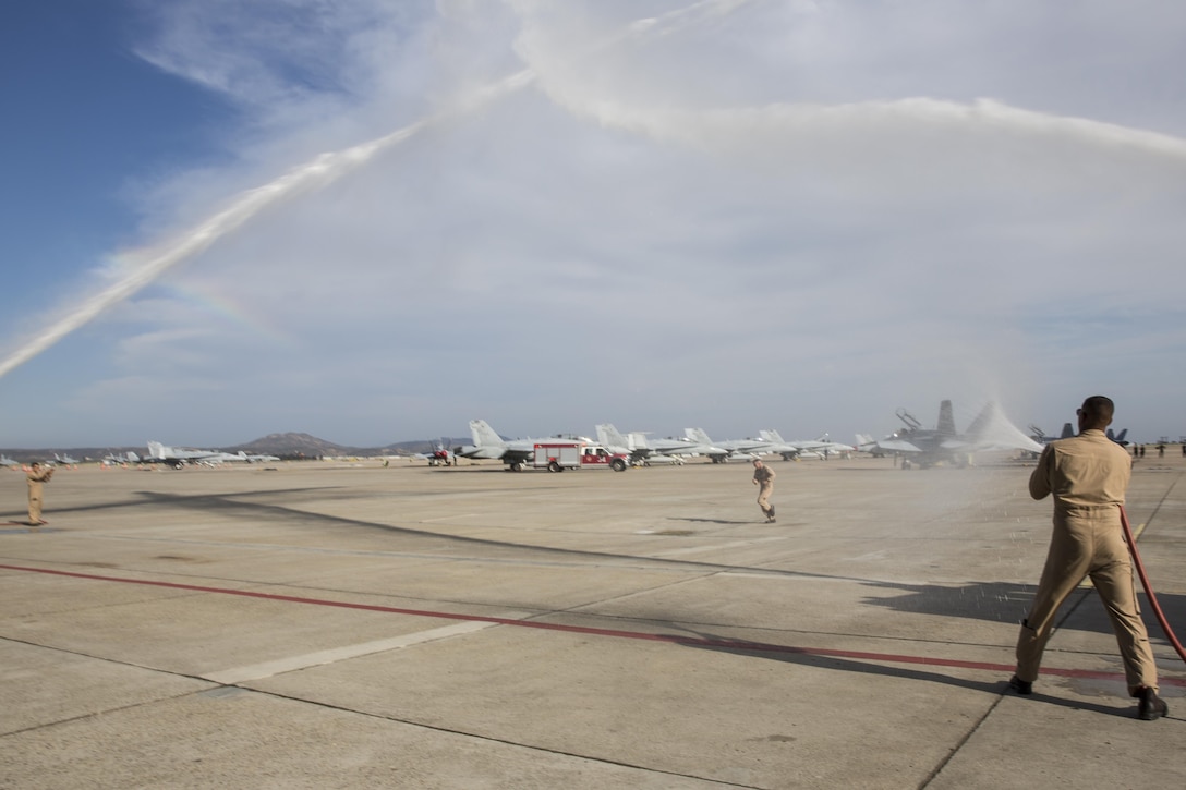 Col. John Farnam, commanding officer of Marine Corps Air Station Miramar, runs across the flightline as Marines with Aircraft Rescue and Firefighting (ARFF) douse him with water for a traditional “wet down” aboard MCAS Miramar, California, August 17. Marines and family members greeted Farnam after his return from his last flight as commanding officer of MCAS Miramar. (U.S. Marine Corps photo by Sgt. Lillian Stephens/Released)