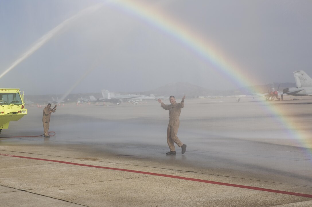 Col. John Farnam, commanding officer of Marine Corps Air Station Miramar, walks beneath an artificial shower made by Marines with Aircraft Rescue and Firefighting (ARFF) aboard MCAS Miramar, California, August 17. Family members and Marines celebrated his last flight as MCAS Miramar’s commanding officer with a traditional “wet down” following Farnam’s last flight as commanding officer. (U.S. Marine Corps photo by Sgt. Lillian Stephens/Released)