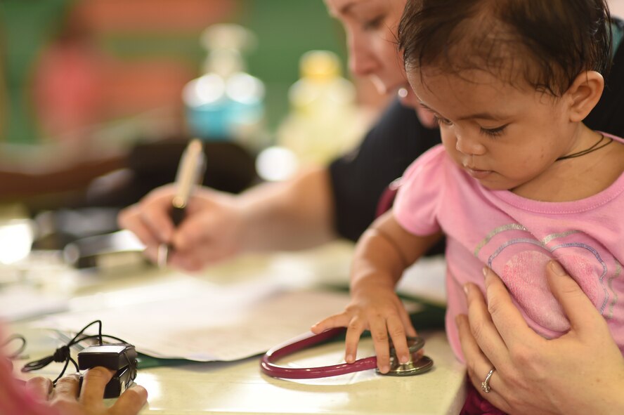Trica, a 1-year-old from Lila, Bohol province, Philippines, plays with a stethoscope as her mother receives a medical screening from Royal Australian Air Force Cpl. Mia Woolley, medical technician, during the Health Services Outreach provided as part of the Pacific Angel Philippines mission taking place in Lila, Bohol province, Philippines, Aug. 16, 2015. Efforts undertaken during Pacific Angel help multilateral militaries in the Pacific improve and build relationships across a wide spectrum of civic operations, which bolsters each nation’s capacity to respond and support future humanitarian assistance and disaster relief operations. (U.S. Air Force photo by Tech. Sgt. Aaron Oelrich/Released)