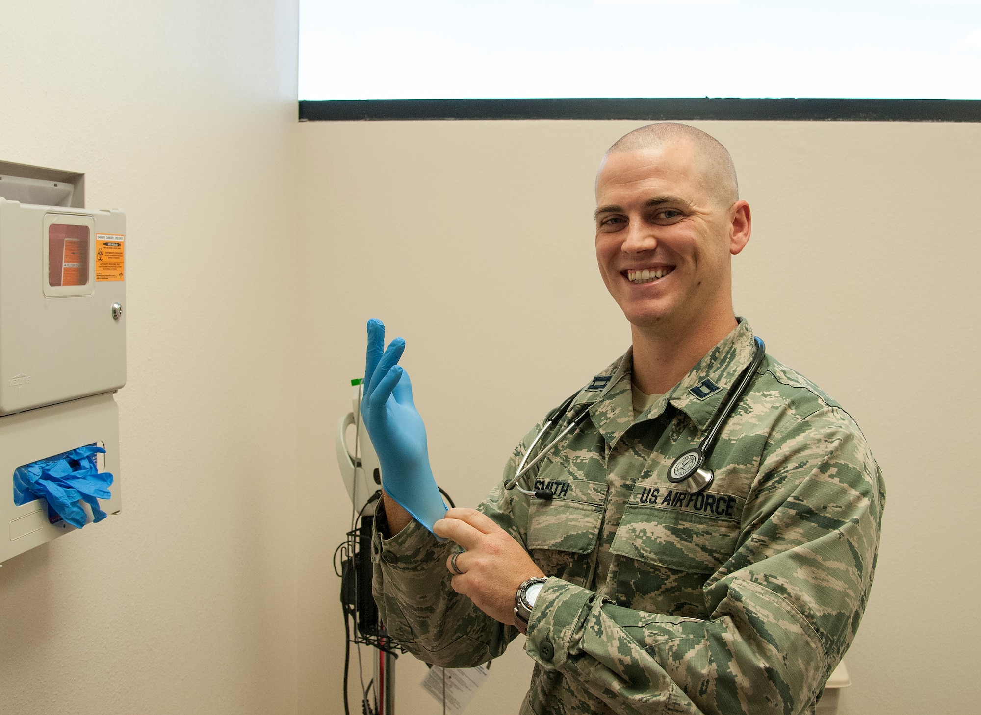 Capt. Nathan Smith, 90th Medical Operations Squadron Nuclear Operations Clinic element chief, puts on a glove as he poses in an examination room in the 90th Medical Group Medical Treatment Facility on F.E. Warren Air Force Base, Wyo, Aug. 19, 2015. Smith recommends patients seek medical treatment if they exhibit the “classic triad” of rhabdomyolyisis symptoms — muscle weakness, muscle pain an dark urine. (U.S. Air Force photo by Senior Airman Jason Wiese)