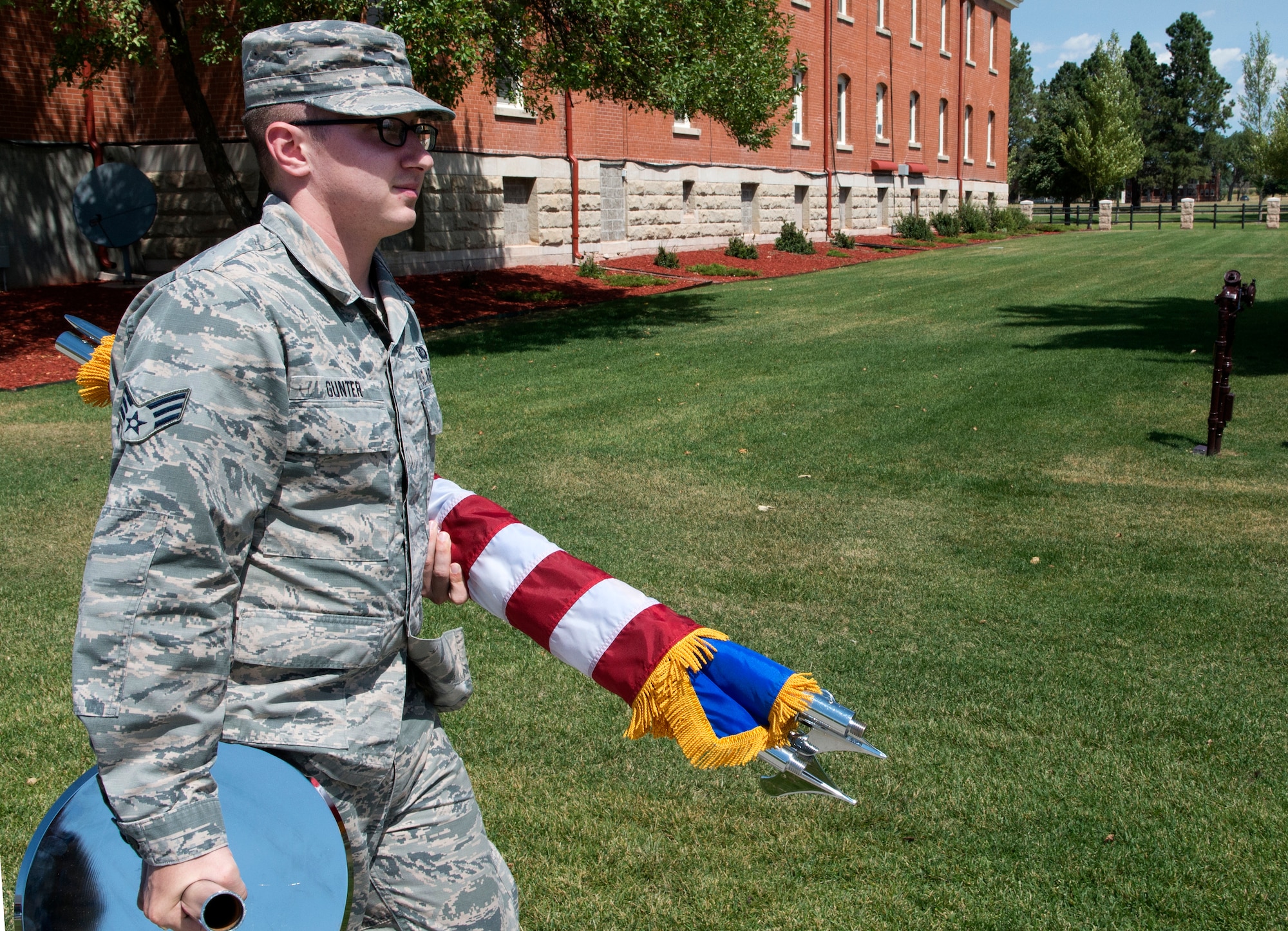 Senior Airman Alex Gunter, 90th Missile Wing protocol office, carries American and Air Force flags out of the wing headquarters building on F.E. Warren Air Force Base, Wyo., Aug. 10, 2015, on his way to set up for a retirement ceremony that day. Part of protocol’s job is the attention to detail at ceremonies, and other events, that can make the difference in rendering the proper respect dignity to an event. (U.S. Air Force photo by Airman 1st Class Malcolm Mayfield/Released)