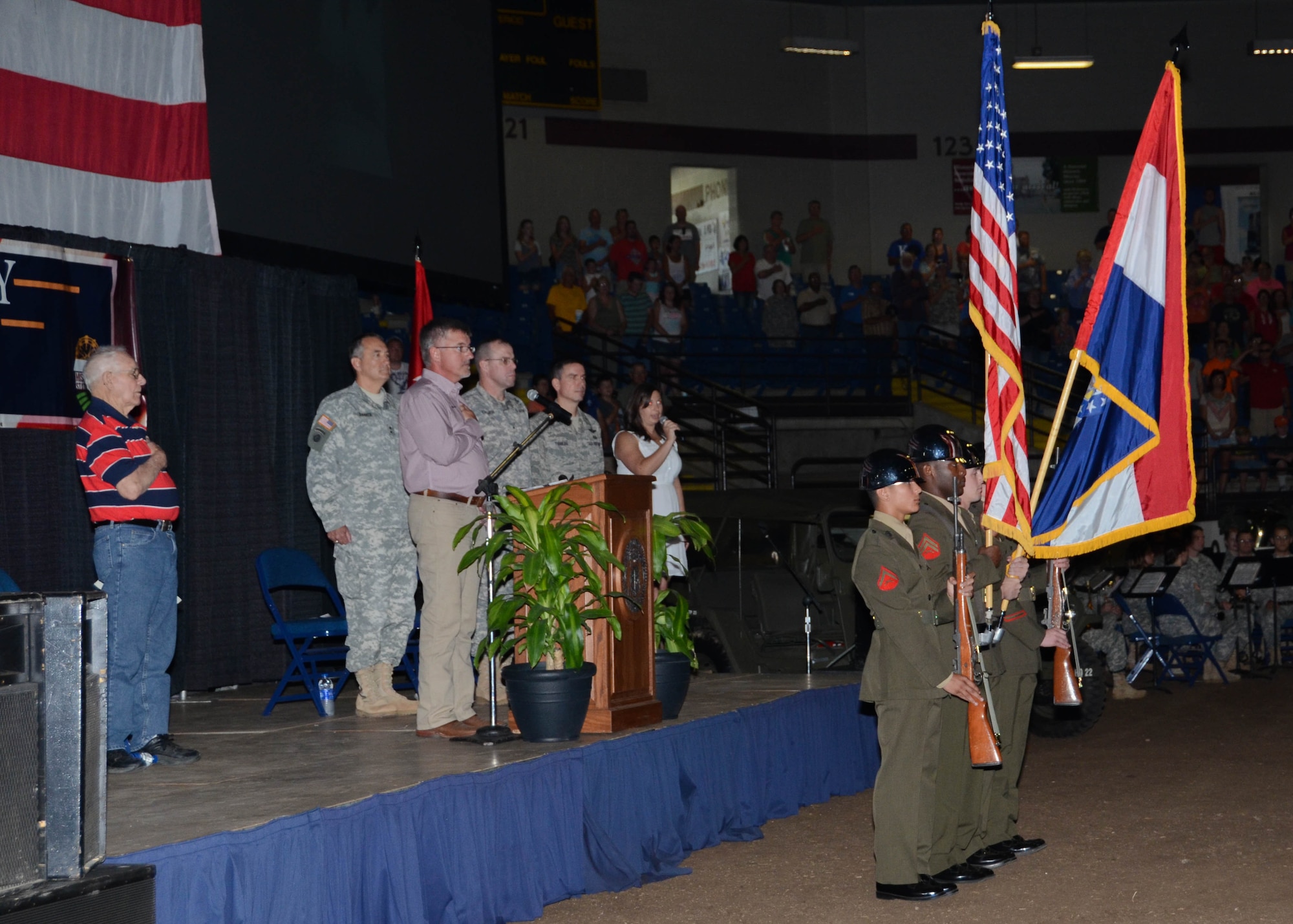 Distinguished guests stand for the singing of the National Anthem by Sarah Alsager, a member in the Missouri Department of Agriculture, and the posting of the colors performed by the Missouri National Guard Funeral Honors Color Guard during the Military Appreciation ceremony at the Missouri State Fair, August 16, 2015. (U.S. Air National Guard photo by Staff Sgt. Brittany Cannon)