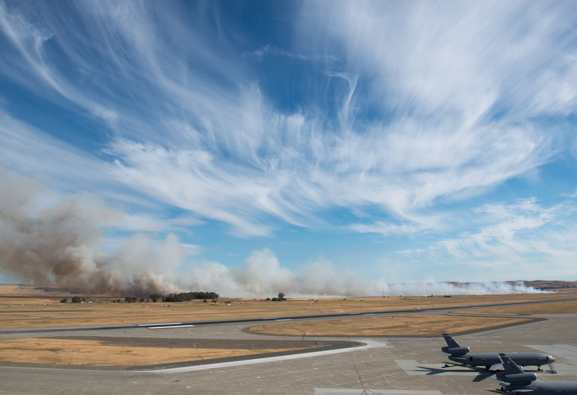 Firefighters from the 60th Civil Engineer Squadron at Travis Air Force Base, Calif., scrambled to extinguish a grass fire near the base's flightline, August 10, 2015. Though no aircraft, buildings or people were in immediate danger, the fire eventually scorched more than 125 acres as it moved outside the base perimeter, where local fire crews responded. The cause of the fire is under investigation. (U.S. Air Force photo by Ken Wright)