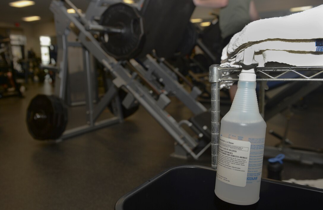 A bottle of disinfectant hangs on a towel rack in a workout room in the fitness center, Aug. 18, 2015, at McConnell Air Force Base, Kan. As a part of maintaining the fitness center, Mugford is responsible for wiping down workout equipment in the fitness center at the end of each shift. (U.S. Air Force photo by Senior Airman Colby L. Hardin)