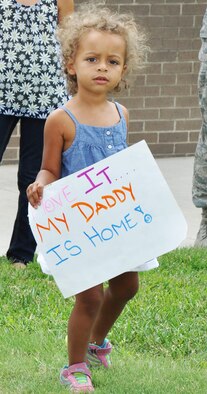 The daughter of Capt. Damian Baskerville, 18th Air Refueling Squadron pilot, holds a handmade sign as she waits for her father, Capt. Damian Baskerville, 18th Air Refueling Squadron pilot, to return Aug. 18, 2015, at McConnell Air Force Base, Kan. Baskerville was part of a small group of 931st Air Refueling Group members that deployed to Southwest Asia. (U.S. Air Force photo by Tech. Sgt. Abigail Klein)
