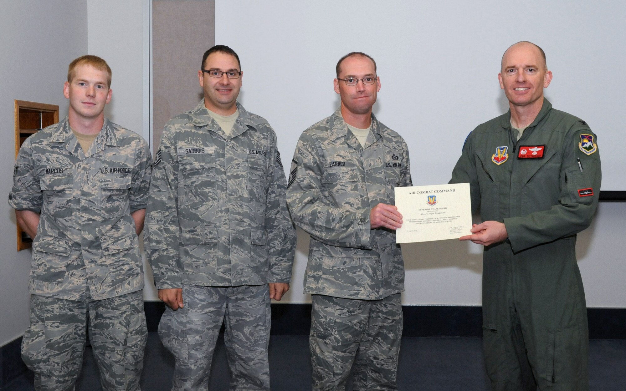 Oregon Air National Guard Col. Paul T. Fitzgerald, 142nd Fighter Wing commander, right, presents the Air Combat Command Superior Team Award to the Aircrew Flight Equipment team in attendance for a briefing following the Unit Effectiveness Inspection, Aug. 18, 2015, Portland Air National Guard Base, Ore. The three members representing the entire team assigned to the 142nd Fighter Wing Operations Group are (left-right) Airman 1st Class Cory Marcus, Tech. Sgt. Gregory Gadbois and Master Sgt. Mike Larner. (U.S. Air National Guard photo by Master Sgt. Shelly Davison, 142nd Fighter Wing Public Affairs) 