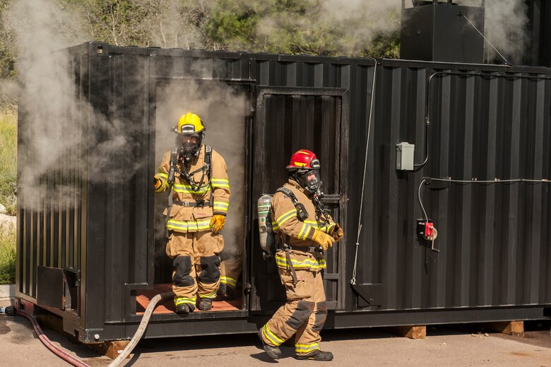 CHEYENNE MOUNTAIN AIR FORCE STATION, Colo. – Firefighters with the 721st Civil Engineer Squadron exit the training facility during flash over fire training at the base training area, Aug. 18, 2015. The new training equipment allows them to see how oxygen interacts with fire and how it would affect a fire in real life. (U.S. Air Force photo by Airman 1st Class Rose Gudex)