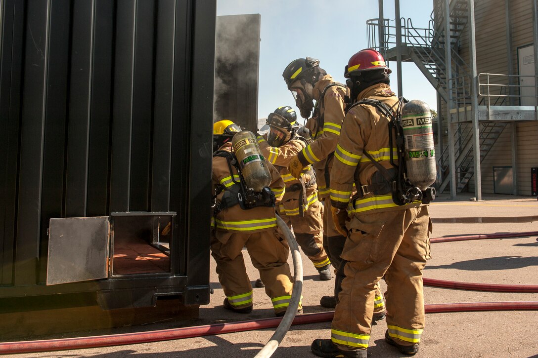 CHEYENNE MOUNTAIN AIR FORCE STATION, Colo. – Firefighters from the 721st Civil Engineer Squadron enter their new training facility during flash over fire training at the base training area, Aug. 18, 2015. The new equipment is essentially a metal box that can contain a fire while firefighters evaluate how oxygen affects smoke and fire patterns. (U.S. Air Force photo by Airman 1st Class Rose Gudex)