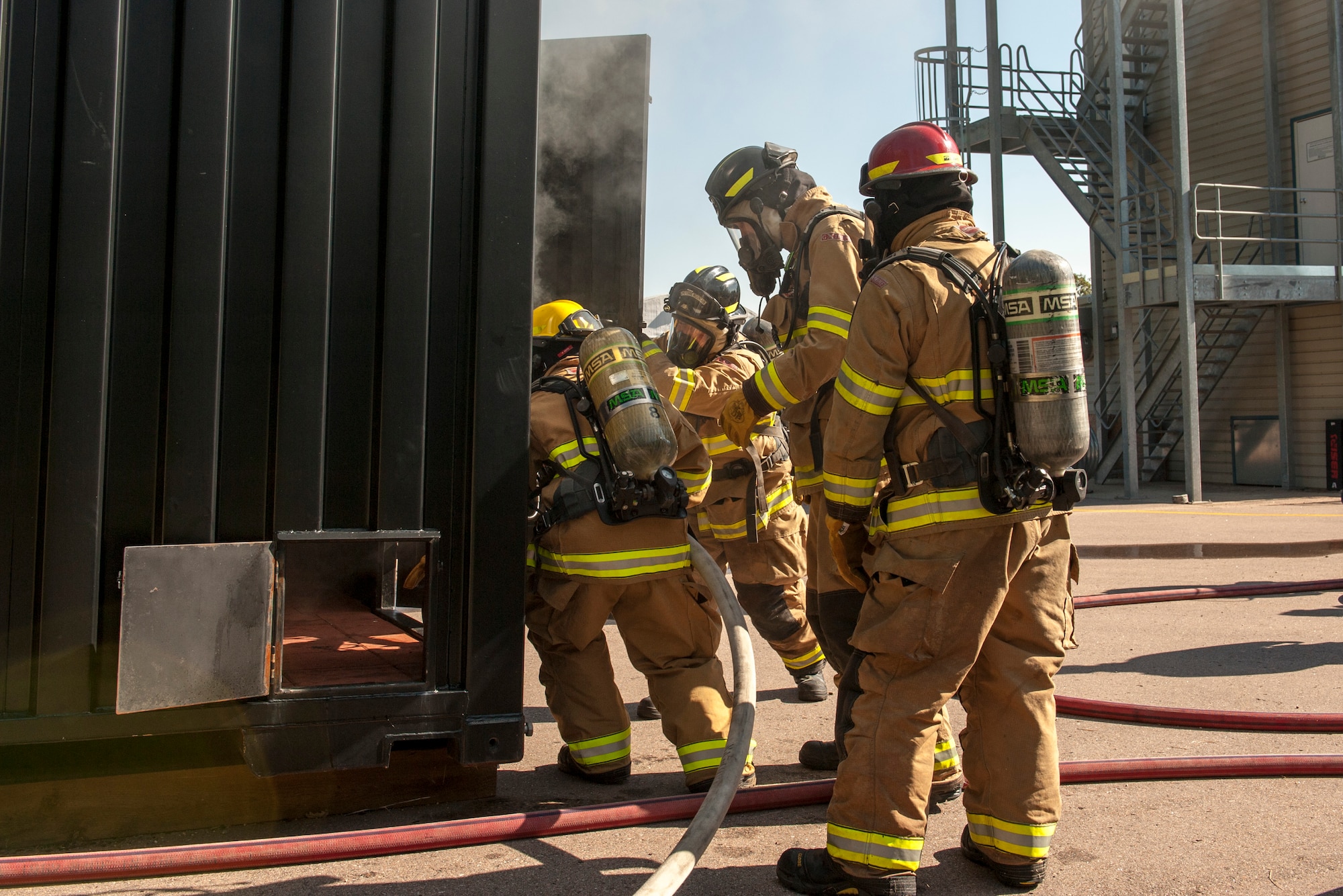 CHEYENNE MOUNTAIN AIR FORCE STATION, Colo. – Firefighters from the 721st Civil Engineer Squadron enter their new training facility during flash over fire training at the base training area, Aug. 18, 2015. The new equipment is essentially a metal box that can contain a fire while firefighters evaluate how oxygen affects smoke and fire patterns. (U.S. Air Force photo by Airman 1st Class Rose Gudex)
