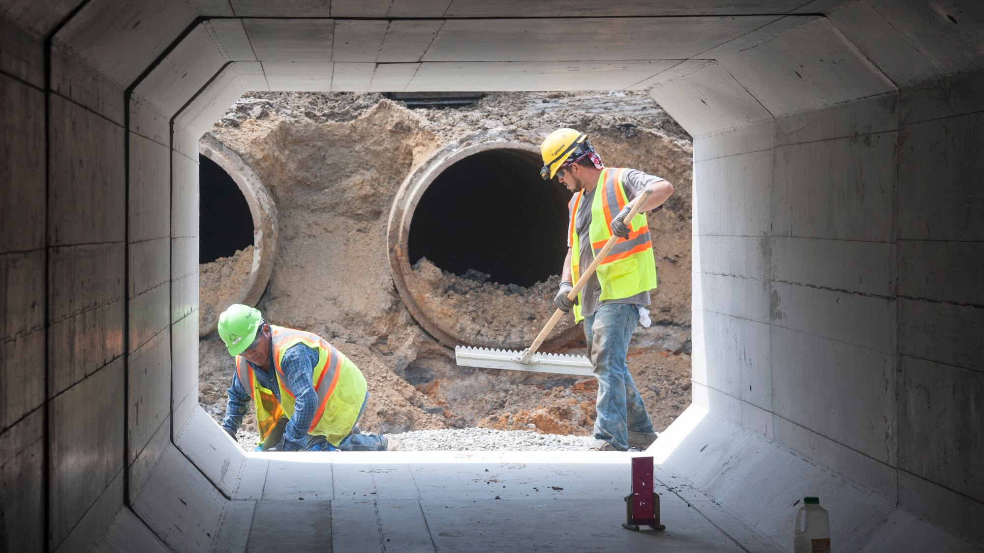 Construction workers level dirt and stone August 12, 2015, on Dover Air Force Base, Del. Before laying the concrete boxes, a level and sturdy base must be set to ensure minimal shifting occurs during the lifetime of the culverts. The work is part of a $98.3 million runway repair project. (U.S. Air Force photo/Senior Airman Jared Duhon)