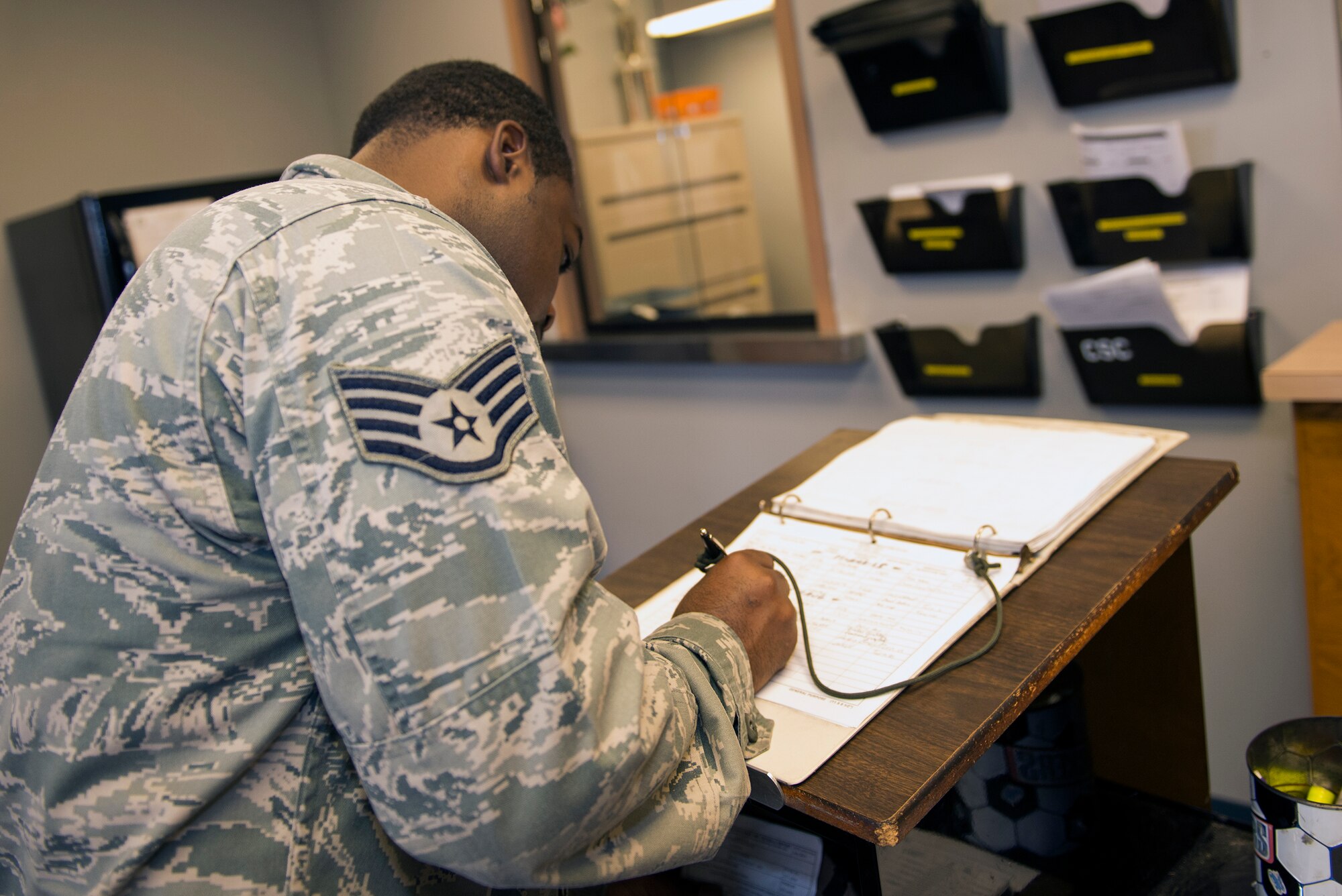 U.S. Air Force Staff Sgt. Donald Henderson, 23d Logistics Readiness Squadron individual protection craftsman, signs into the 23d LRS Vehicle Management Flight’s customer service vehicle pick-up and return log Aug. 11, 2015, at Moody Air Force Base, Ga.  The customer service section shop is the vehicle turn in center and is responsible for tracking and accounting all scheduled maintenance on vehicle assets. (U.S. Air Force photo by Airman 1st Class Greg Nash/Released) 