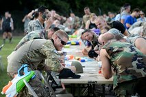 Airmen bang their fists on tables in acceptance of a comment during the 3rd annual Combat Dining In, Aug. 14, 2015, at Seymour Johnson Air Force Base, North Carolina. Banging fists was the preferred method of clapping during the event, as it encourages maximum volume. (U.S. Air Force photo/Senior Airman Brittain Crolley)