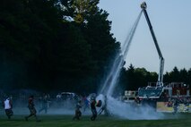 The 4th Civil Engineer Squadron fire department rains down gallons of water during the 3rd annual Combat Dining In, Aug. 14, 2015, at Seymour Johnson Air Force Base, North Carolina. Squadrons were given six hours before the event to construct forts and load their water supplies. (U.S. Air Force photo/Senior Airman Brittain Crolley)