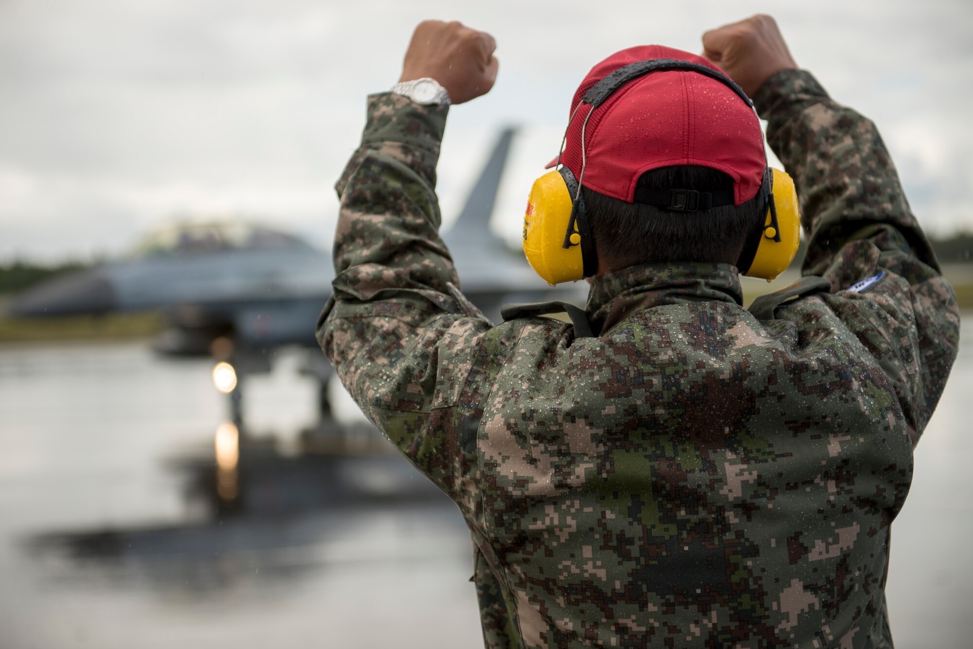 Republic of Korea Air Force (ROKAF) Warrant Officer Dongjun Lee, a ROKAF maintenance officer, signals to the pilots of a ROKAF F-16D Fighting Falcon after marshaling the aircraft through an unexpected rainstorm for a RED FLAG-Alaska (RF-A) 15-3 sortie, Aug. 11, 2015 at Eielson Air Force Base, Alaska. RF-A sorties are conducted for the full two-weeks, rain or shine, barring extreme inclement weather, providing participants with unparalleled training in the world’s largest instrumented air, ground and electronic combat training range in the world, the Joint Pacific Alaska Range Complex. (U.S. Air Force photo by 1st Lt. Elias Zani/Released)