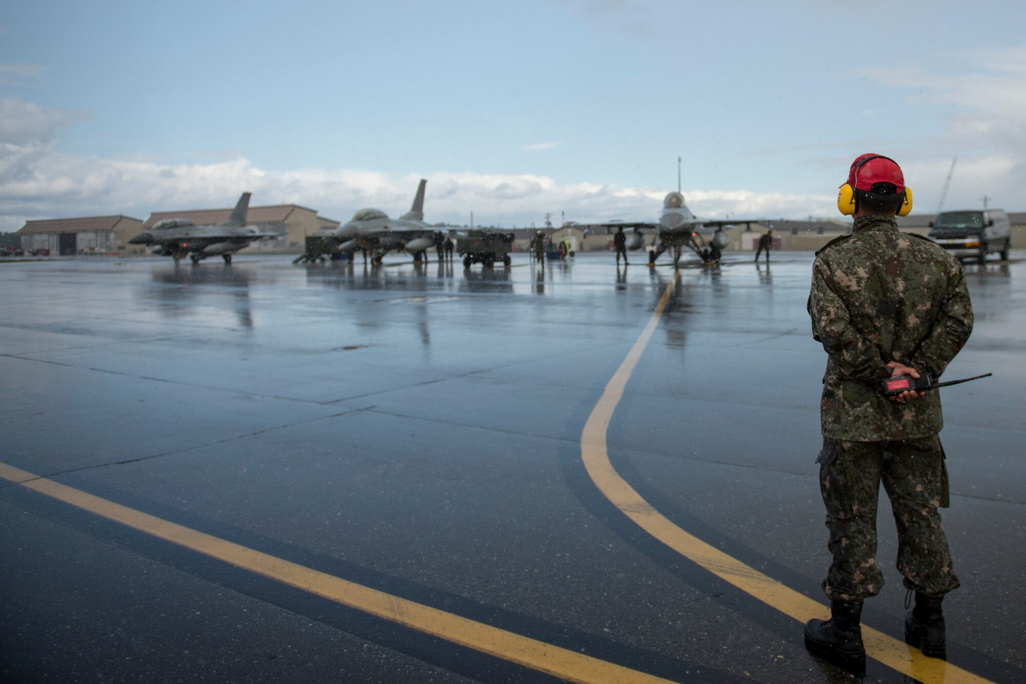 Republic of Korea Air Force (ROKAF) Warrant Officer Dongjun Lee, a ROKAF maintenance officer, waits through an unexpected rainstorm to marshal aircraft for a RED FLAG-Alaska (RF-A) 15-3 sortie, Aug. 11, 2015 at Eielson Air Force Base, Alaska. RF-A sorties are conducted for the full two-weeks, rain or shine, barring extreme inclement weather, providing participants with unparalleled training in the world’s largest instrumented air, ground and electronic combat training range in the world, the Joint Pacific Alaska Range Complex. (U.S. Air Force photo by 1st Lt. Elias Zani/Released)