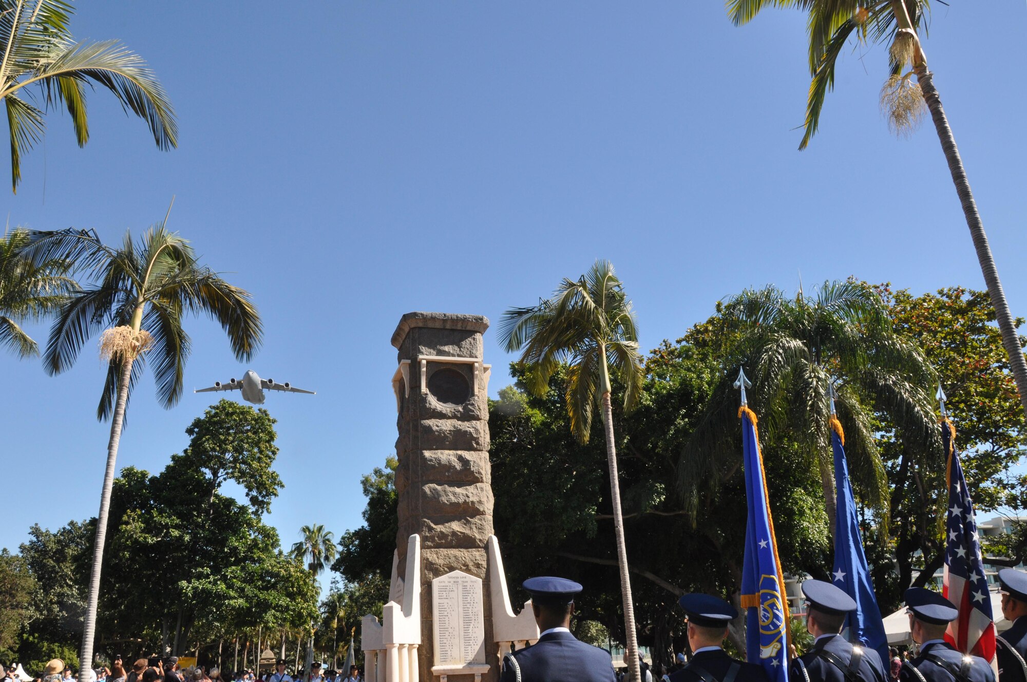 A Royal Australian Air Force C-17 preforms a flyover at the start of the Townsville, Australia VP70 Memorial Service as members of the Yokota Air Base Honor Guard stand at attention, Aug 15, 2015. The service took place at ANZAC Park and honored all those who gave their lives in the defense of their country and led to victory in the Pacific 70 years ago. (U.S. Air Force photo by Capt. George M. Tobias/Released)