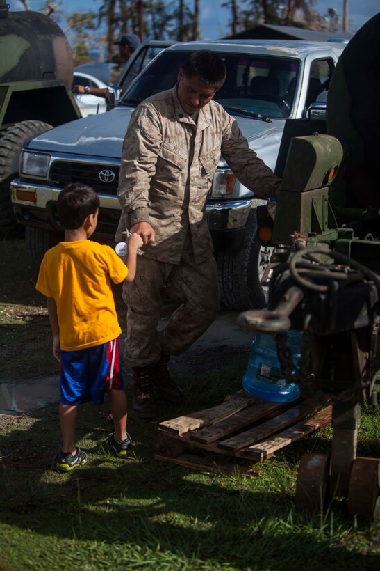 A young boy bumps fists with Sgt. Theron Nez as U.S. Marines with Combat Logistics Battalion 31, 31st Marine Expeditionary Unit, distribute water to local civilians during typhoon relief efforts in Saipan, Aug. 12, 2015. The 31st MEU and the ships of the Bonhomme Richard Amphibious Ready Group are assisting local and federal agencies with distributing emergency relief supplies to Saipan after the island was struck by Typhoon Soudelor Aug. 2-3. (U.S. Marine Corps photo by Gunnery Sgt. Ismael Pena/Released)
