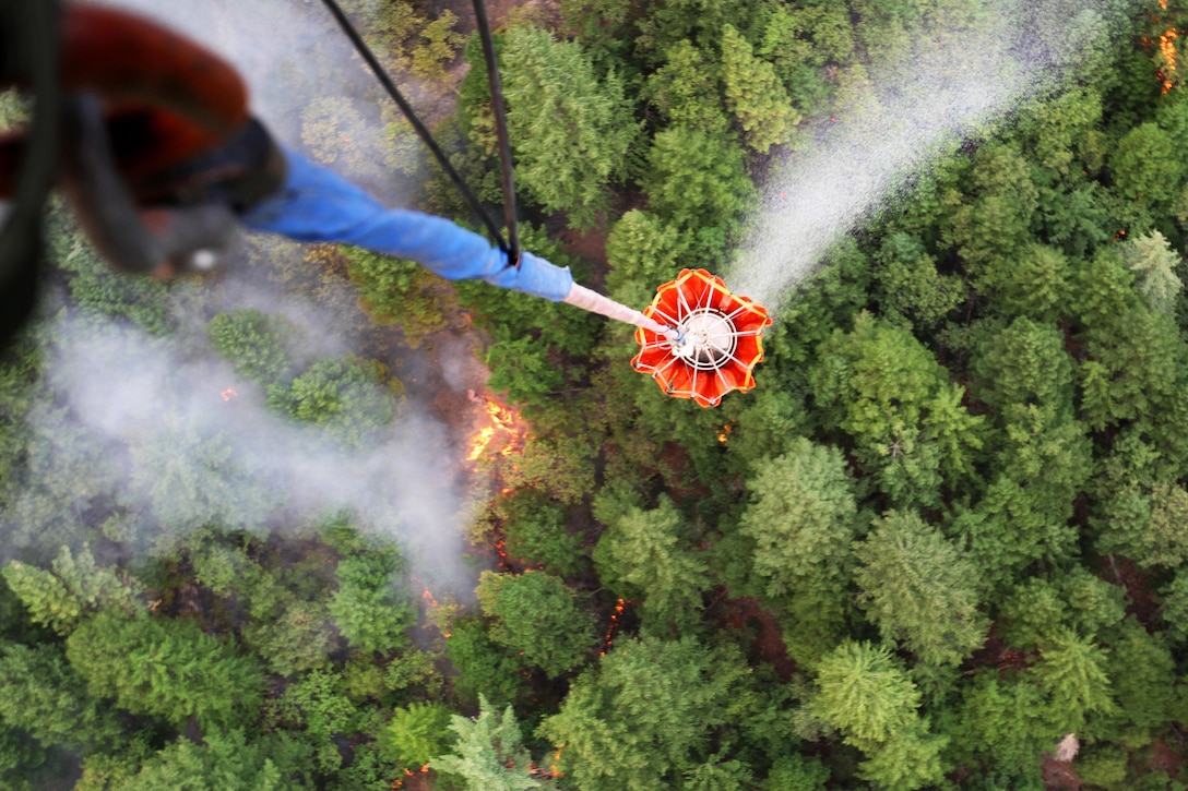 A CH-47 Chinook helicopter suspends a large bucket of water to douse a wildfire in Shasta County near Redding, Calif., Aug. 19, 2015. The helicopter, part of an effort to battle more than a dozen wildfires in California, is assigned to the California National Guard's 1st Battalion, 126th Aviation Regiment.