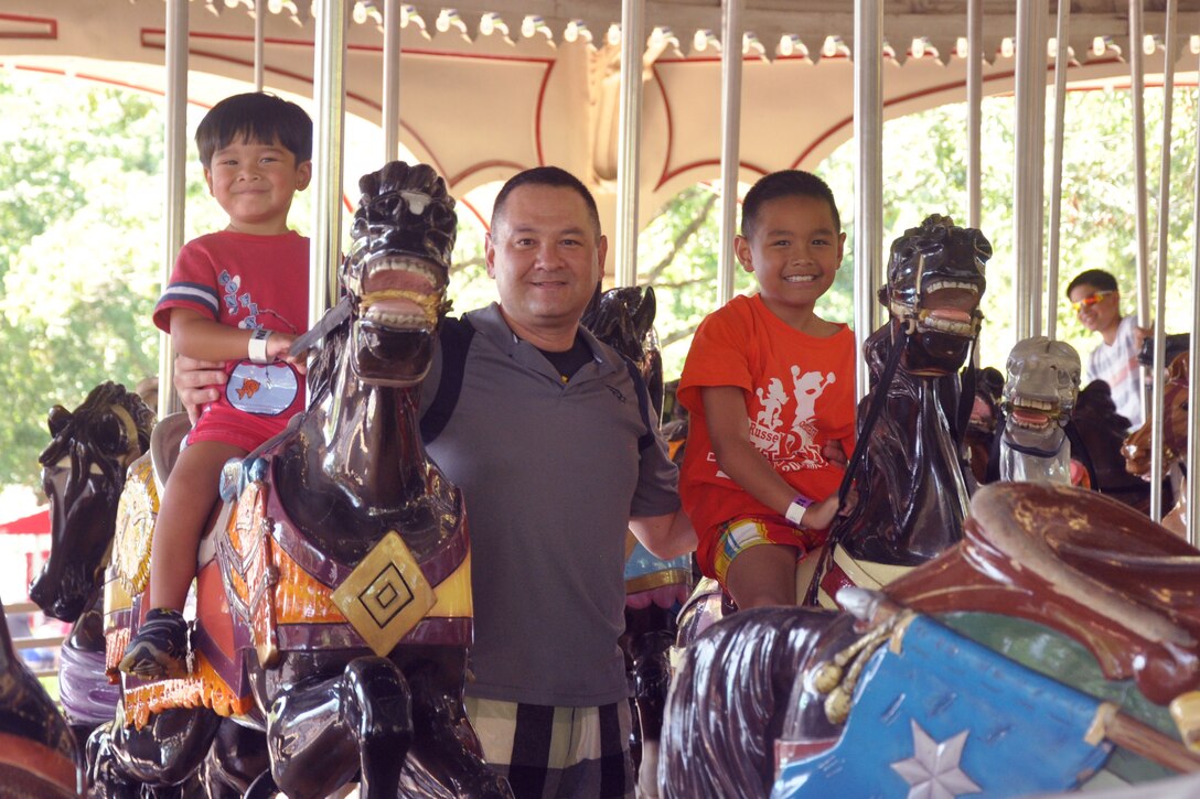 Maj. Christopher Smith, Headquarters Service Battalion logistics officer, treats his two boys to a carousel ride at Kings Dominion theme park, Aug. 12. The Smith family of four visited the park for the first time. The H&S Bn. conducted a family day which included discounted tickets and a free lunch for registered military families.