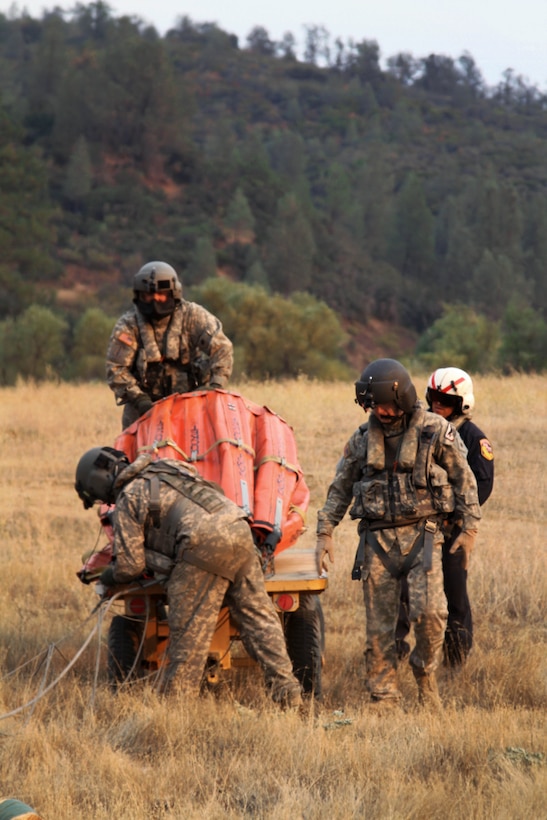 Army Sgts. Matthew Hammond snf Jameson Freymond; Capt. Frank Abril, rear right, Cal Fire's military helicopter manager; and Army Chief Warrant Officer 4 Craig Hannon load a bucket firefighting system into their CH-47 Chinook helicopter in Redding, Calif., Aug. 19, 2015. California Army National Guard photo by Staff Sgt. Eddie Siguenza