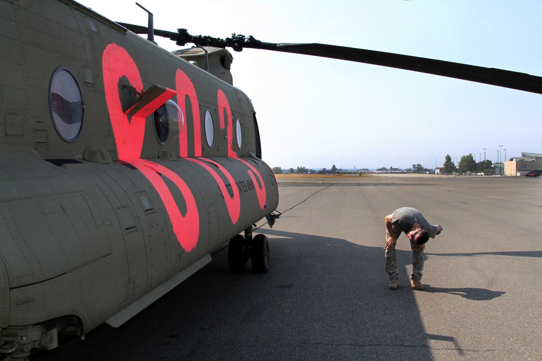 Army Chief Warrant Officer 4 Craig Hannon checks his CH-47 Chinook helicopter at Redding Airport in Redding, Calif., Aug. 19, 2015, before dropping water over the Northern California wildfires. Hannon is a pilot assigned to the California Army National Guard's 1st Battalion, 126th Aviation Regiment. California Army National Guard photo by Staff Sgt. Eddie Siguenza