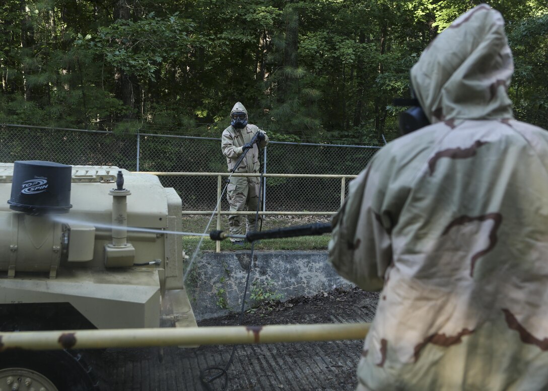 Marines with 2nd Combat Engineer Battalion spray down a tactical vehicle while wearing Mission Oriented Protective Posture gear at Fort A.P. Hill, Va., Aug. 16, 2015. The Marines conducted the training in order to practice decontamination procedures involving Chemical Biological Radiological and Nuclear defense as part of a deployment for training exercise where the battalion trained on provisional infantry skills to prepare for upcoming deployments. (U.S. Marine Corps photo by Cpl. Michelle Reif/Released)