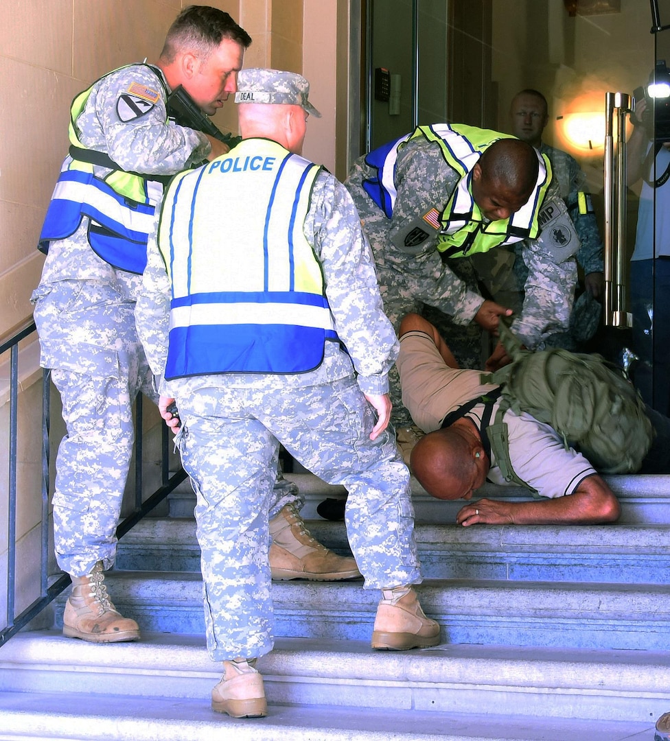 Members of Army South military police apprehend Rafael Torres, Army South antiterrorism officer, who is playing the role of an active shooter, walking out of the U.S. Army South headquarters building during an active shooter exercise Aug. 13. 