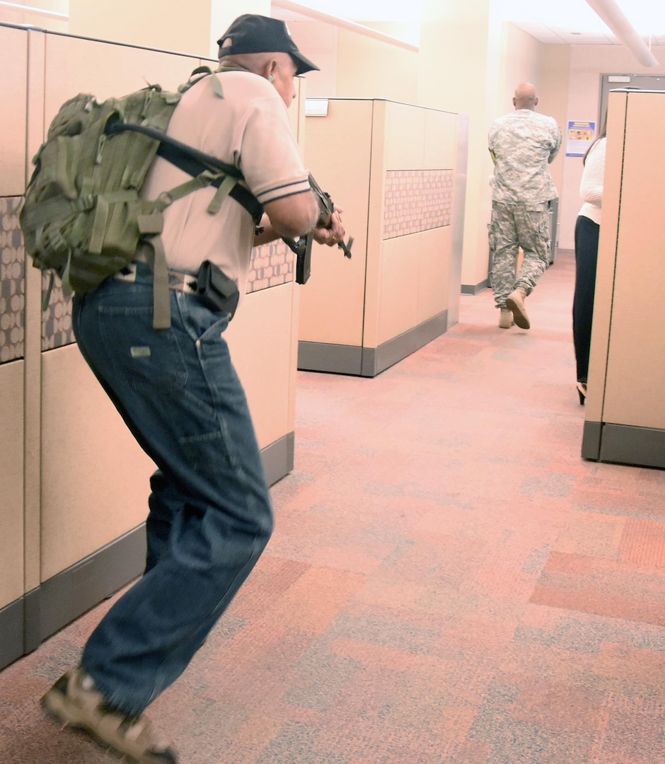 Playing the role of active shooter, Rafael Torres (left), antiterrorism officer for Army South, moves through the different offices in the U.S. Army South headquarters building on Fort Sam Houston simulating attacking employees during an active shooter exercise Aug. 13. 