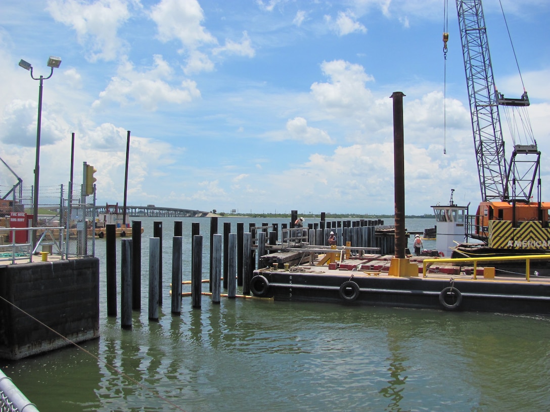 Pilings are augured and driven into place using a crane mounted on a barge.