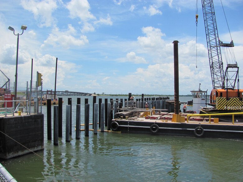 Pilings are augured and driven into place using a crane mounted on a barge.