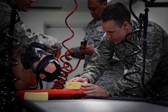 U.S. Air Force Tech. Sgt. Eric Hood, 51st Medical Operations Squadron medical decontamination instructor, demonstrates the proper way to use a sponge when decontaminating a patient on a litter on Osan Air Base, Republic of Korea, Aug. 18, 2015. The entire 51st Medical Group participated in multiple stages of readiness training to ensure the hospital and its patients would be safe from intruders and contaminants. (U.S. Air Force photo by Tech. Sgt. Travis Edwards/Released)

