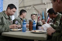 U.S. Air Force Senior Airman Kenny Batallas, 374th Operations Support Squadron aircraft flight equipment technician, samples authentic Thai food while talking with members of the Royal Thai Air Force at Red Flag-Alaska at Joint Base Elmendorf-Richardson, Alaska, Aug. 18, 2015. RED FLAG-Alaska offers participants a chance to build cultural competence and relationships with each other during an exercise environment, aimed at improving efficiency and familiarity between partner nations in the case of real-world contingencies. (U.S. Air Force photo by Staff Sgt. Cody H. Ramirez/Released)