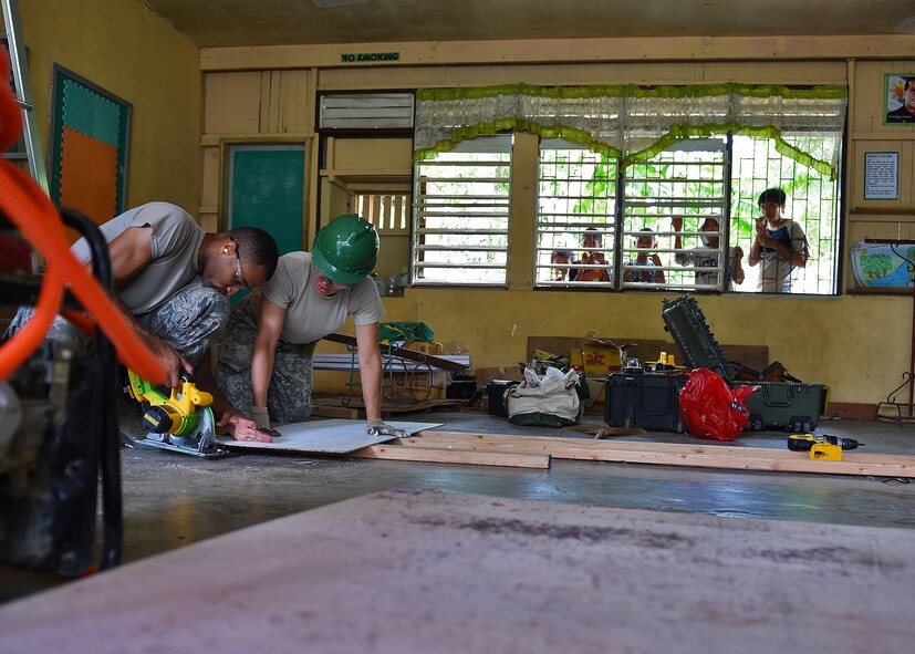Working as members of a engineering civic action team for Pacific Angel Philippines, Airmen 1st Class Bryan Wallace, from the 354th Civil Engineering Squadron, Eielson Air Force Base, Alaska, (left) and Army Staff Sgt. Andrea White, from the 84th Engineer Battalion, 130th Engineer Brigade, Schofield Barracks, Hawaii, work to trim a piece of wood to be installed on the ceiling of Dao Elementary in the Bohol Provence, Philippines, Aug. 20, 2015. Dao Elementary is one of six schools repaired by the U.S. and its Indo-Asia-Pacific allies during Pacific Angel Philippines. Efforts undertaken during Pacific Angel help multilateral militaries in the Pacific improve and build relationships across a wide spectrum of civic operations, which bolsters each nation’s capacity to respond and support future humanitarian assistance and disaster relief operations. (U.S. Air Force photo by Tech. Sgt. Aaron Oelrich/Released)