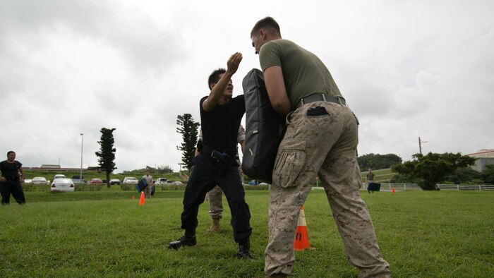 A Japanese security guard executes a knee strike during nonlethal weapons and level one oleoresin capsicum spray training aboard Camp Foster, Okinawa, Japan, Aug. 14. According to Delekto, the security augmentation force instructor and staff noncommissioned officer with mobile training team, Provost Marshal’s Office, Marine Corps Base Camp Smedley D. Butler, Marine Corps Installations Pacific, nonlethal weapons training includes all weapons and techniques that are not inherently deadly, such as batons, defensive tactics, pepper-based spray, and mechanical-advantage control holds. 