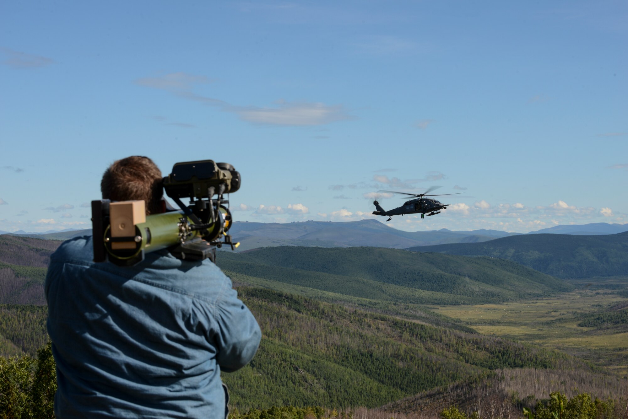U.S. Air Force contractor Mike Young with the 353rd Combat Training Squadron, shines an ultraviolet light that simulates an RPG at a U.S. Air Force HH-60G Pave Hawk helicopter assigned to the 210th Rescue Squadron, Joint Base Elmendorf-Richardson, Alaska, during a rescue demonstration Aug. 17, 2015, for RED FLAG-Alaska (RF-A )15-3 at the Joint Pacific Alaska Range Complex. The demonstration was for the Executive Observer Program, which is designed to present Pacific Air Force’s premier multinational large force employment exercise while building partnerships with senior airpower leaders from the global community. (U.S. Air Force photo by Senior Airman Ashley Nicole Taylor/Released)
