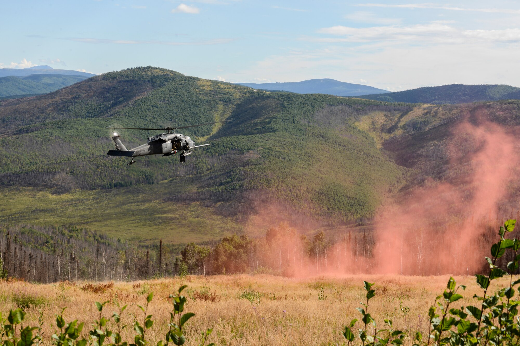 A U.S. Air Force HH-60G Pave Hawk helicopter assigned to the 210th Rescue Squadron, Joint Base Elmendorf-Richardson, Alaska, hovers over a deployed smoke signal for a rescue demonstration Aug. 17, 2015,during RED FLAG-Alaska (RF-A) 15-3 at the Joint Pacific Alaska Range Complex. The demonstration was for the Executive Observer Program, which is designed to present Pacific Air Force’s premier multinational large force employment exercise while building partnerships with senior airpower leaders from the global community. (U.S. Air Force photo by Senior Airman Ashley Nicole Taylor/Released)