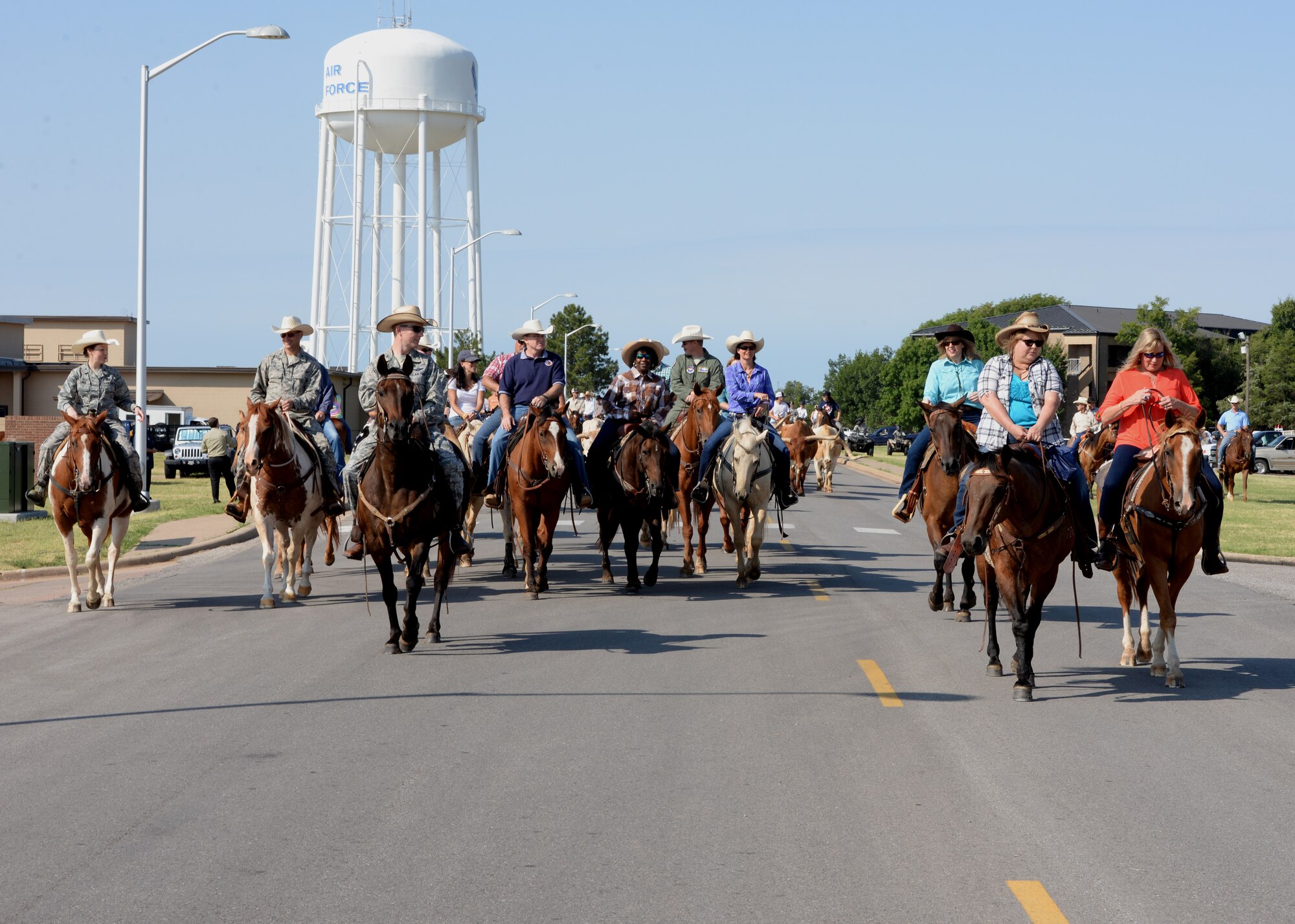 ALTUS AIR FORCE BASE, Okla. – A herd of longhorn cattle are led through the streets of Altus AFB by local ranchers and riders during the annual Altus AFB cattle drive, Aug. 20, 2015. The cattle drive tradition started in 1999 with 15 riders and a herd of roughly 30 longhorn cattle parading through the streets of Altus AFB. (U.S. Air Force photo by Airman 1st Class Megan E. Acs/Released) 