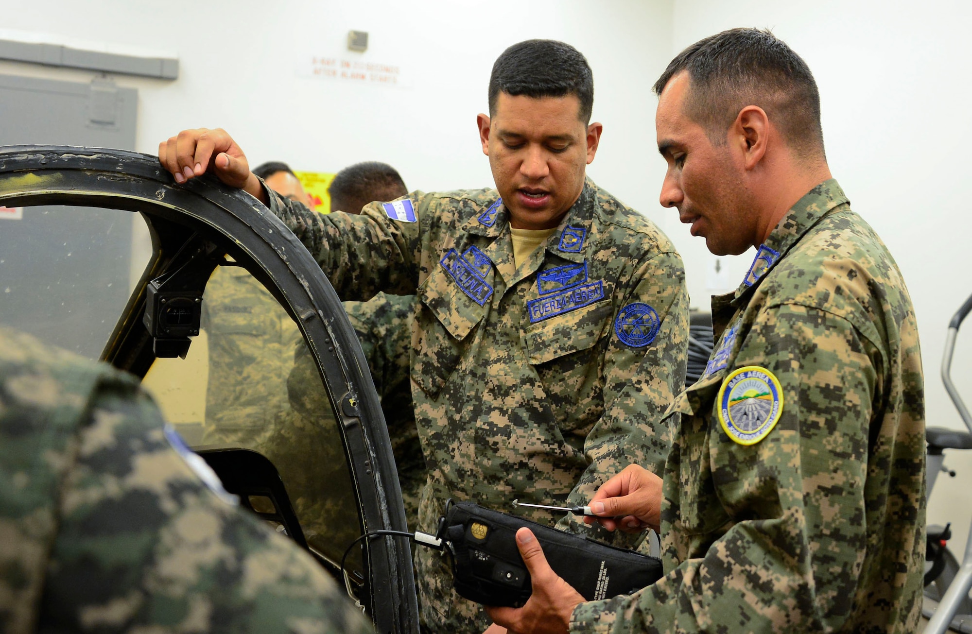 Honduran air force Master Sgts. Josué Molina and Elmer Villeda practice looking for discontinuities using an eddy current in an aircraft canopy during a subject matter expert exchange event with members from the 355th Equipment Maintenance Squadron nondestructive inspections lab on Davis-Monthan AFB, Ariz., Aug. 19, 2015. The eddy current uses a circulating electrical current induced in a conductor by an alternating magnetic field to locate discontinuities. When eddy currents encounter an obstacle, such as a crack, the surrounding currents become distorted. The five members from the Honduran air force teamed up with 12th Air Force (Air Forces Southern) and the 355th EMS for a subject matter expert exchange that focused on a variety of nondestructive inspections lab processes and maintenance safety standards. (U.S. Air Force photo by Tech. Sgt. Heather Redman/Released)