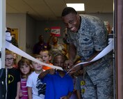 Col. Brandon Parker, 2nd Bomb Wing vice commander, and a child cut through a ribbon together, signifying the opening of the new Child Development Center gross motor classroom at Barksdale Air Force Base, La., Aug. 20, 2015. The classroom provides an alternate location for children to continue to focus on their gross motor skills during extreme weather conditions. (U.S. Air Force photo/Senior Airman Jannelle Dickey)
