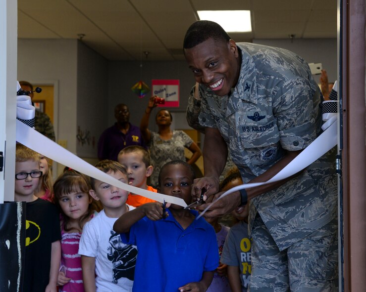 Col. Brandon Parker, 2nd Bomb Wing vice commander, and a child cut through a ribbon together, signifying the opening of the new Child Development Center gross motor classroom at Barksdale Air Force Base, La., Aug. 20, 2015. The classroom provides an alternate location for children to continue to focus on their gross motor skills during extreme weather conditions. (U.S. Air Force photo/Senior Airman Jannelle Dickey)